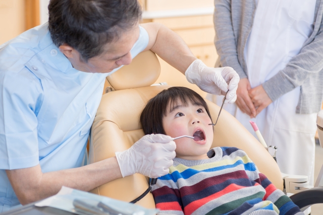子どもが歯医者で定期検診をしている画像